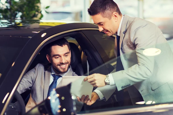 Homem feliz com negociante de carro em auto show ou salão de beleza — Fotografia de Stock