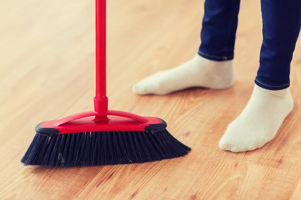 Close up of woman legs with broom sweeping floor — Stock Photo, Image