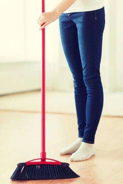 Close up of woman legs with broom sweeping floor — Stock Photo, Image