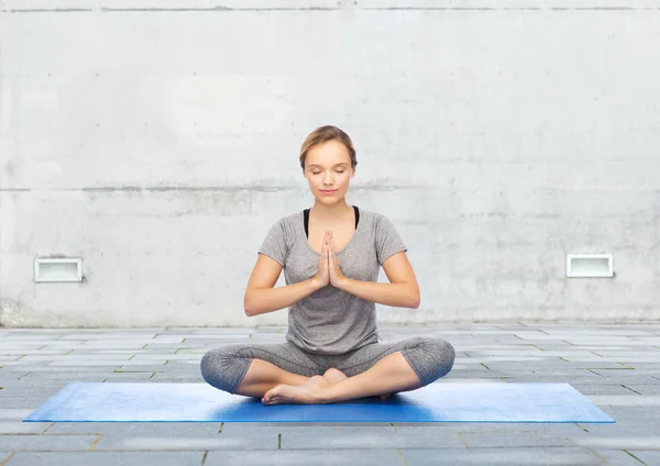 Mujer haciendo meditación de yoga en pose de loto en la estera —  Fotos de Stock