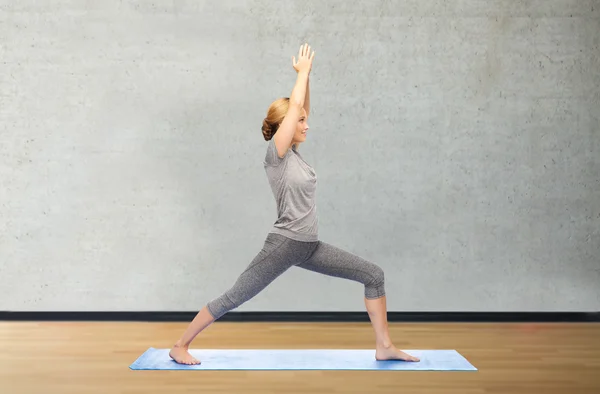 Женщина делает воин yoga поза на циновке — стоковое фото