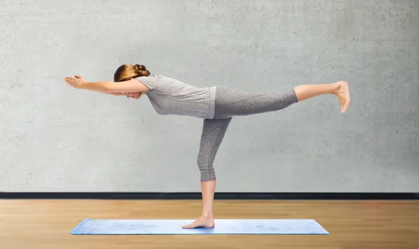 Женщина делает воин yoga поза на циновке — стоковое фото