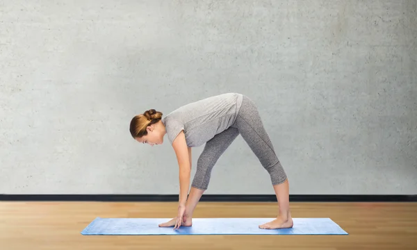 Женщина делает yoga интенсивная поза растяжения на циновке — стоковое фото