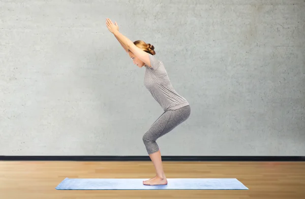 Mujer haciendo yoga en silla pose sobre estera — Foto de Stock