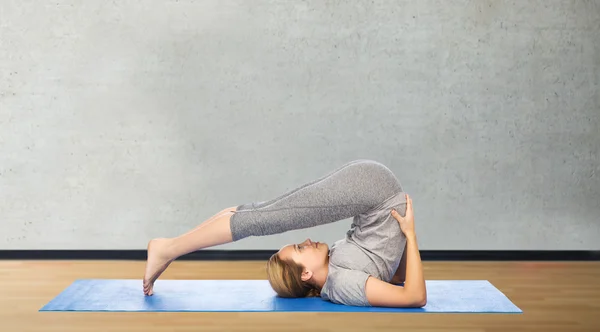 Donna che fa yoga in posa aratro sul tappeto — Foto Stock