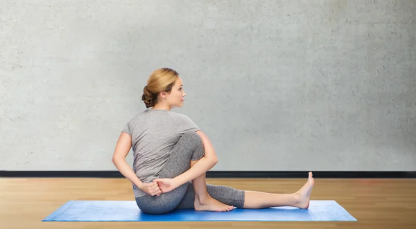 Mujer haciendo yoga en actitud de giro en la estera —  Fotos de Stock