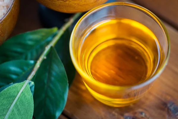 Nahaufnahme von Honig im Glas mit Blättern auf Holz — Stockfoto