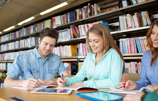 Счастливые студенты с планшетным ПК в библиотеке — стоковое фото