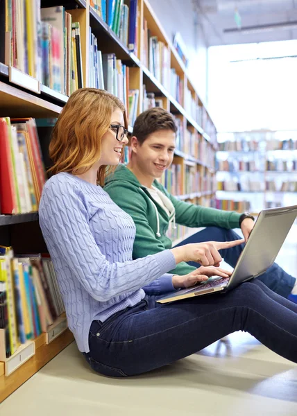 Zadowoleni uczniowie z laptopa w bibliotece — Zdjęcie stockowe