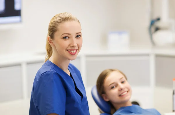 Szczęśliwa kobieta dentysty z dziewczyna pacjenta w klinice — Zdjęcie stockowe