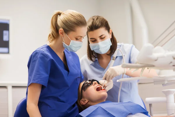 Dentistas mulheres que tratam os dentes da menina paciente — Fotografia de Stock