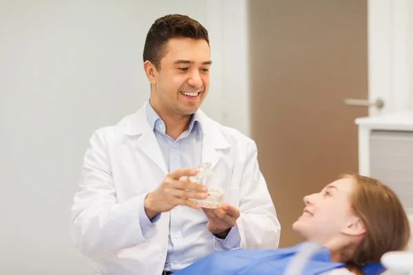 Glücklicher Zahnarzt zeigt Patientin Kiefer-Layout — Stockfoto