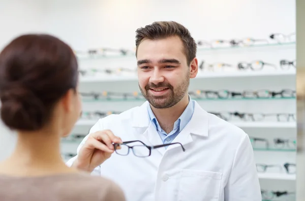 Optiker schenkt Frau Brille im Optikgeschäft — Stockfoto