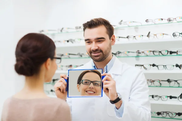 Woman in glasses looking to mirror at optics store — Stock Photo, Image