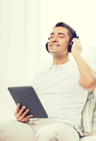 Usmívající se muž s tablet pc a sluchátka doma — Stock fotografie