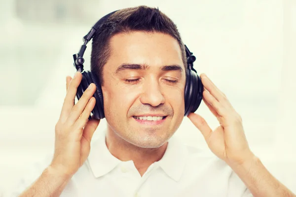 Gelukkig man in koptelefoon luisteren naar muziek thuis — Stockfoto