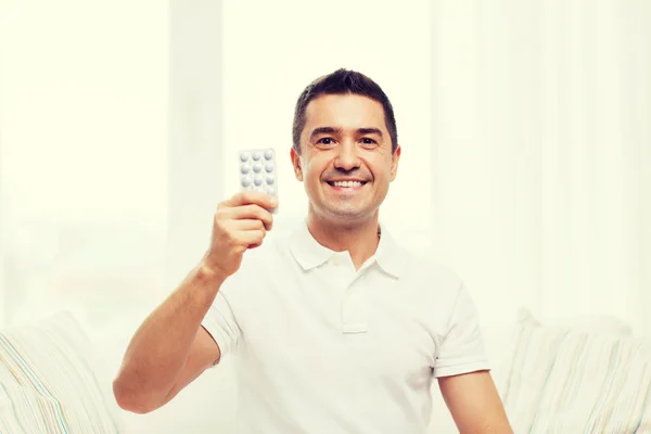 Happy man showing pack of pills at home — Stock Photo, Image