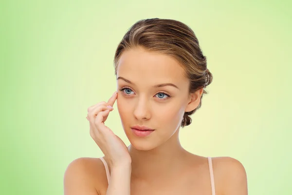 Jonge vrouw aanbrengen crème op haar gezicht — Stockfoto