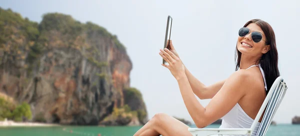 Leende kvinna med tablet pc sola på stranden — Stockfoto