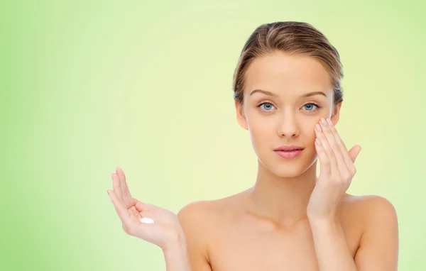 Mujer joven aplicando crema en su cara —  Fotos de Stock