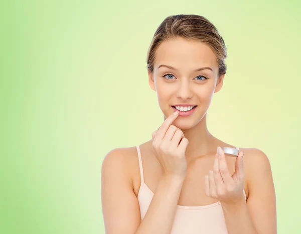 Sorridente giovane donna applicando balsamo labbra alle labbra — Foto Stock