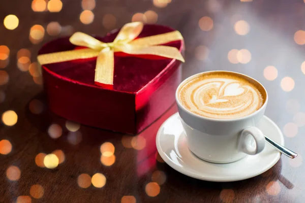 Закрытие подарочной коробки и чашки кофе на столе — стоковое фото