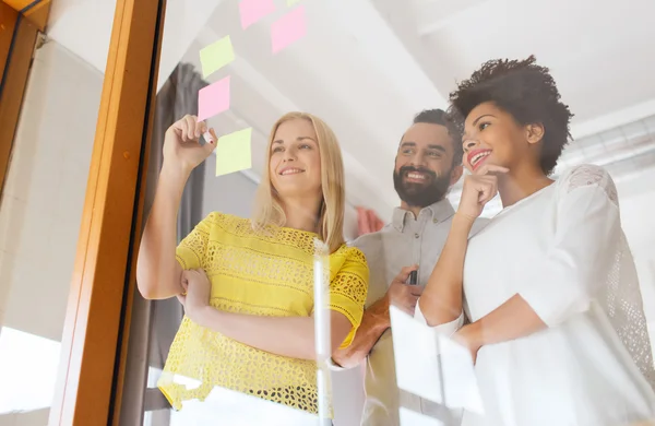 Feliz equipo creativo escribiendo en pegatinas en la oficina — Foto de Stock