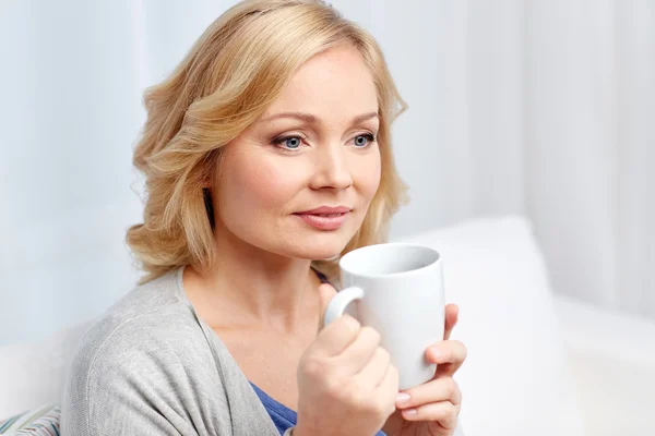 Donna sorridente con tazza di tè o caffè a casa — Foto Stock