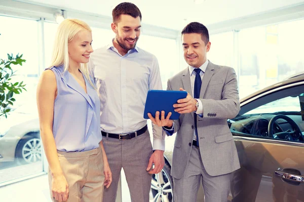 Casal feliz com revendedor de carro em auto show ou salão — Fotografia de Stock