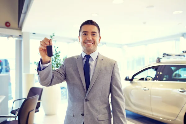 Hombre feliz que muestra la llave en el salón auto del espectáculo o del coche —  Fotos de Stock