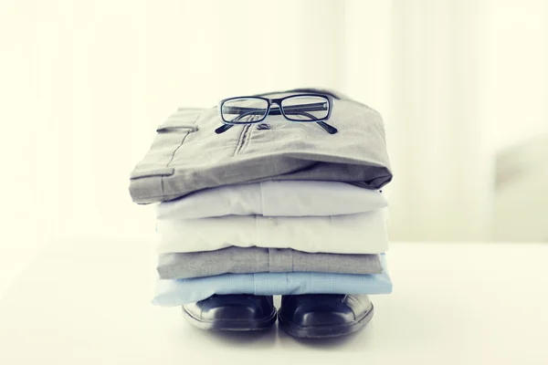 Close up of folded male shirts and shoes on table — Stock Photo, Image