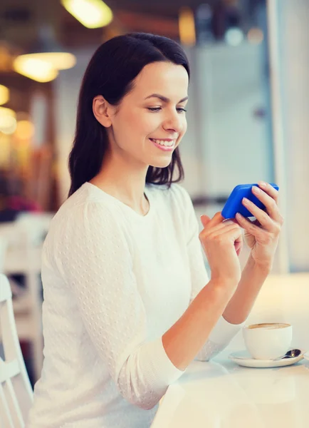 Mujer sonriente con teléfono inteligente y café en la cafetería — Foto de Stock