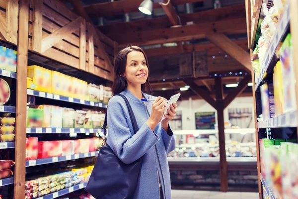 Mulher feliz com bloco de notas no mercado — Fotografia de Stock