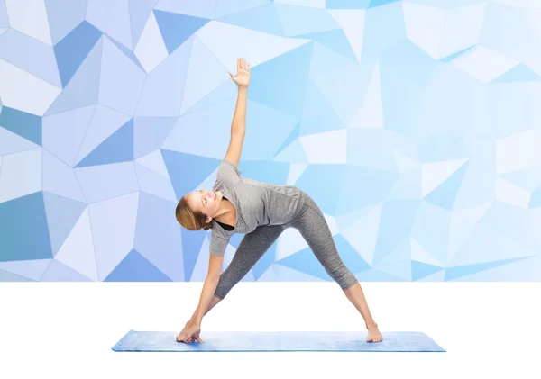 Frau posiert Yoga-Dreieck auf Matte — Stockfoto