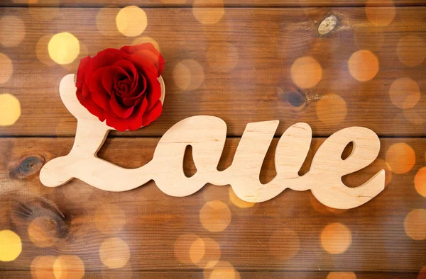 Close up of word love cutout with red rose on wood — Stock Photo, Image