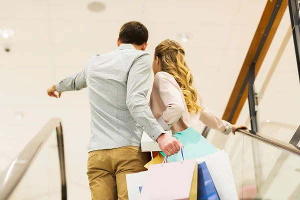 Happy young couple with shopping bags in mall — Stock Photo, Image