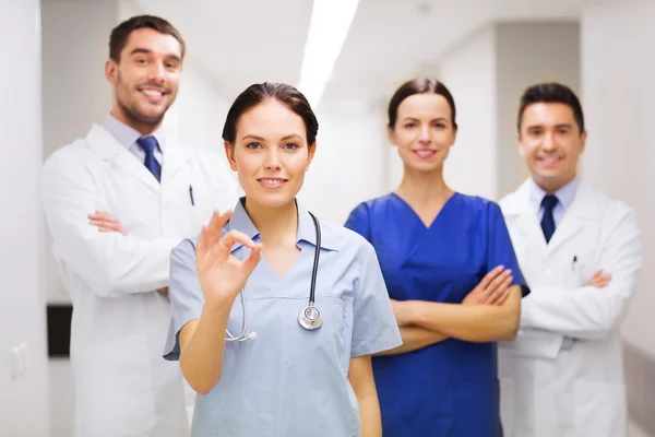 Gruppo di medici in ospedale mostrando segno mano ok — Foto Stock