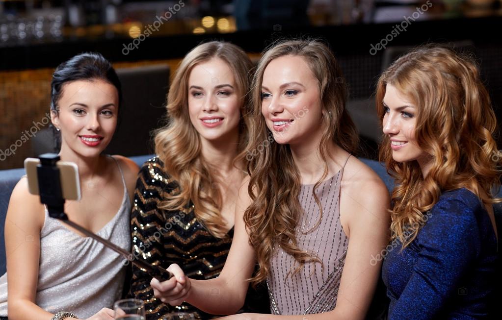 party, technology, nightlife and people concept - smiling friends with  smartphone taking selfie in club. Stock Photo