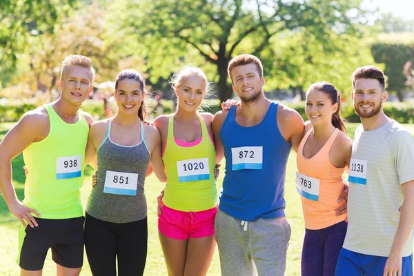 Amigos felizes ou casal com números de crachá de corrida — Fotografia de Stock