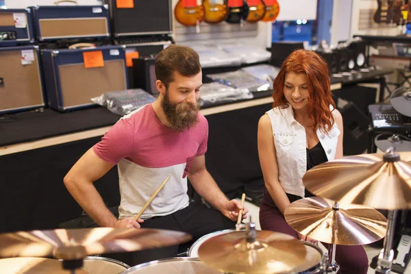 Happy man and woman playing cymbals at music store — Stock Photo, Image