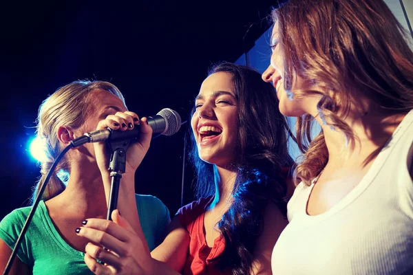 Happy young women singing karaoke in night club — Stock Photo, Image