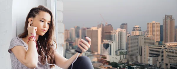Девочка-подросток со смартфоном и наушниками — стоковое фото