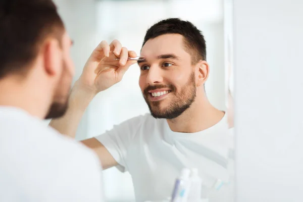 Hombre con pinzas de depilación ceja en el baño — Foto de Stock