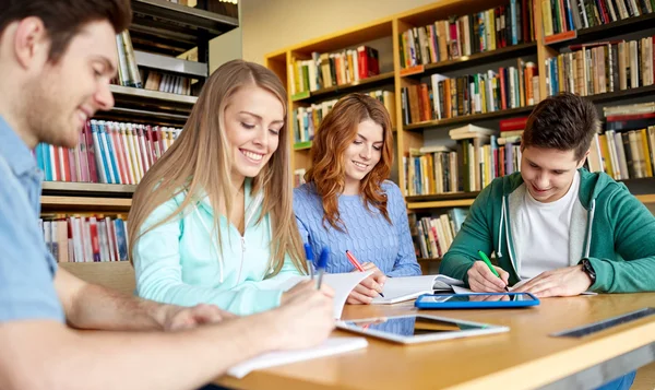 Alunos felizes com tablet pc na biblioteca — Fotografia de Stock