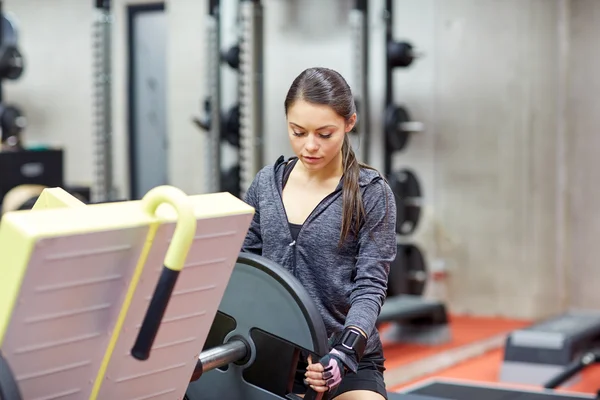 Mujer joven ajustando la máquina de prensa de piernas en el gimnasio — Foto de Stock