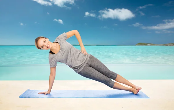 Vrouw maken yoga in zijkant plank pose op de mat — Stockfoto