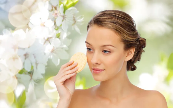 Young woman cleaning face with exfoliating sponge — Stock Photo, Image