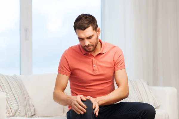 Homem infeliz sofrendo de dor na perna em casa — Fotografia de Stock
