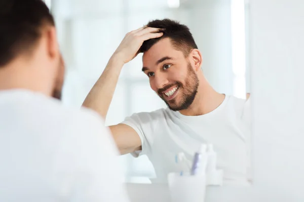 Happy young man looking to mirror at home bathroom — Stock Photo, Image
