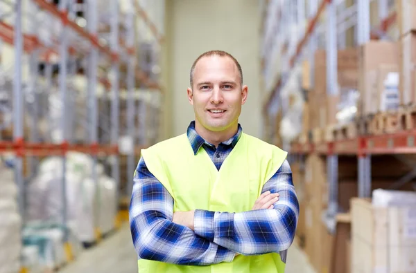 Happy man in reflective safety vest at warehouse — Stock Photo, Image